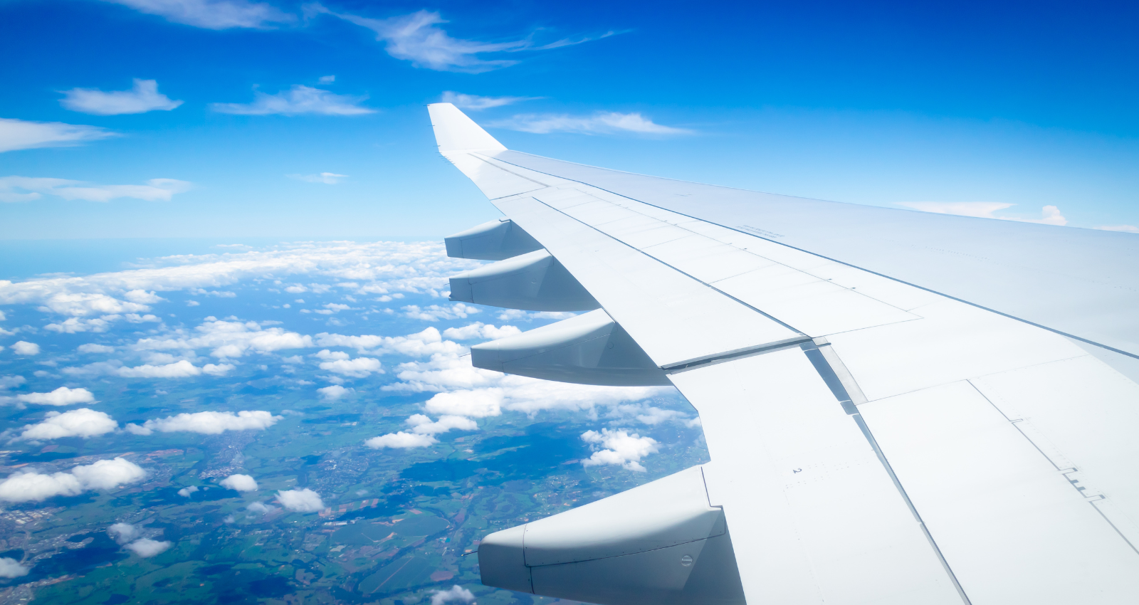 Blue sky with clouds and planes wing. View from planes window