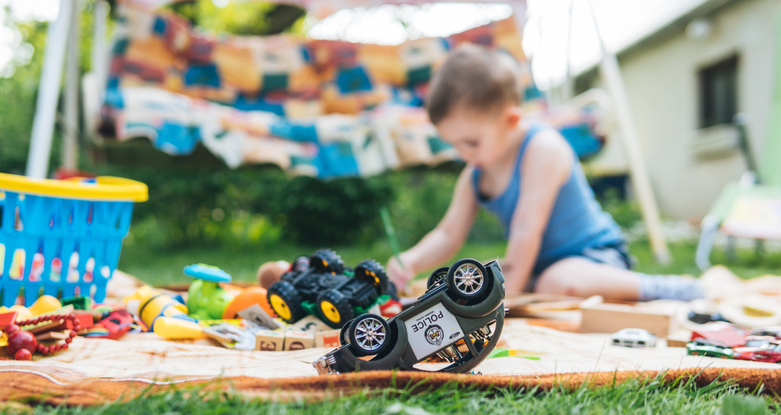 young boy playing in garden with toy cars